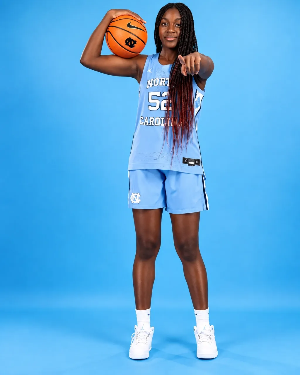 Noelle Bofia, number 52 for North Carolina, holding a basketball overhead and pointing